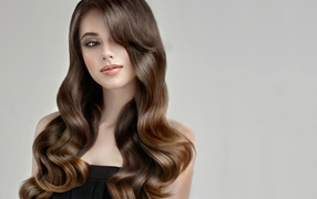 Молодая девушка с красивыми длинными волосами на сером фоне