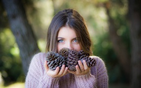 Молодая девушка с шишками в руках