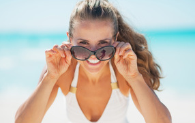 Молодая улыбающаяся девушка в солнечных очках 
