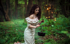 Молодая девушка колдунья варит зелье в лесу