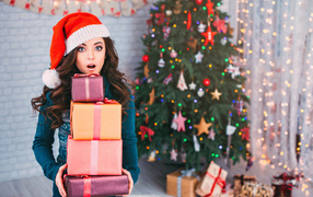 Surprised girl with gifts at the Christmas tree