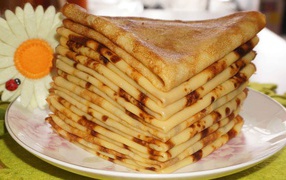 Стопка тонких блинов с ромашкой на Масленицу