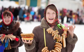 Улыбающаяся девушка с угощениями на праздник Масленица 2018
