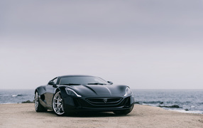 Черный спортивный автомобиль Rimac Concept One на фоне океана