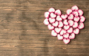 Heart made of heart-shaped sweets on a wooden table