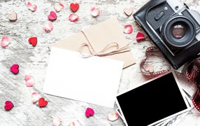 Старый фотоаппарат с фотографиями и маленькими сердечками на столе