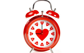 Красный будильник с сердечками на белом фоне