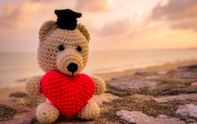 Игрушечный медведь с красным сердцем на фоне неба