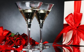 Two glasses with martini, a gift and red roses for your beloved
