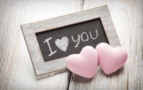 Two pink hearts on a table with a wooden frame
