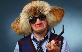 Мужчина в меховой шапке в модных очках с трубкой в руке