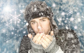 Молодой парень в теплой шапке мерзнет зимой