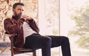 Популярный актер Бен Аффлек сидит на стуле