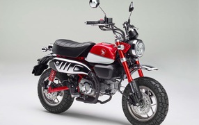 Красный мотоцикл Honda Monkey, 2018 года на сером фоне