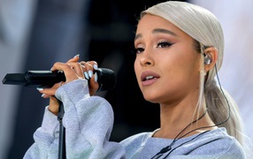 Светловолосая певица Ариана Гранде с микрофоном на сцене 