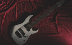 Гитара лежит на красном покрывале