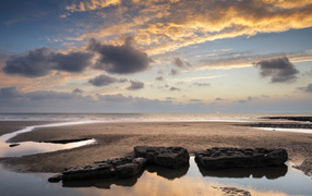 Большие камни в воде на песке под красивым небом