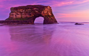 Гора с аркой в океане на фоне красивого неба