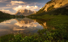 Горы в лучах солнца под красивым небом отражаются в воде
