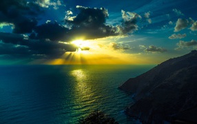 Лучи яркого солнца пробиваются сквозь облака над морем