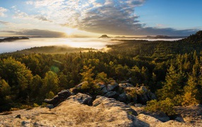 Вид со скалы на покрытый туманом лес и озеро на восходе солнца