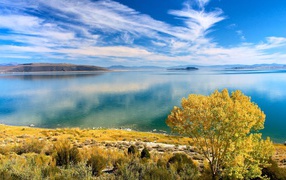 Белые облака в голубом небе отражаются в озере