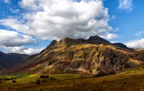 Белые пушистые облака над горой 