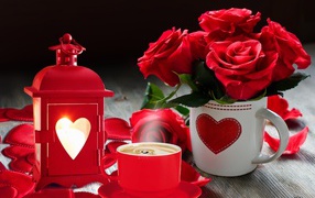 A bouquet of red roses in a cup on a table with a flashlight and a cup of coffee
