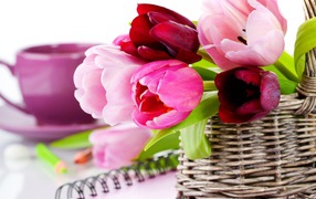 Bouquet of colorful tulips in a basket on a table with a notebook