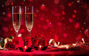 Букет роз и два фужера шампанского с зажженными свечами на красном фоне