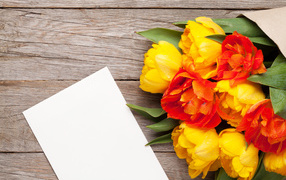 Букет желтых тюльпанов на столе с листом бумаги