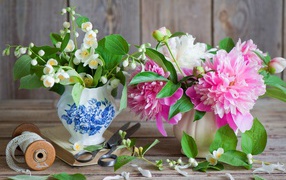 Delicate jasmine and peony flowers in a vase on the table