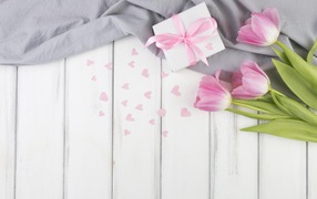 Три розовых тюльпана на столе с подарочной коробкой 