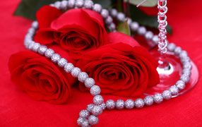 Три красные розы с украшением на красном фоне