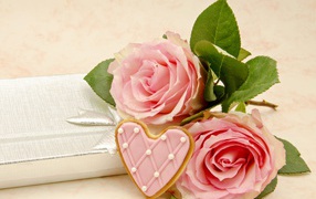 Две розовые розы с печеньем в виде сердца на розовом фоне