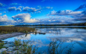 Голубое небо с облаками отражается в озере