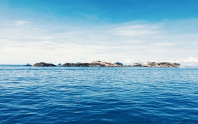 Спокойное синее море со скалами на горизонте