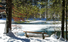 A bench in the park near an ice-covered melting lake in the spring