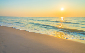 Морские волны на желтом песке на закате солнца летом