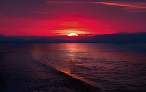 The sunset of the red sun on the sea horizon