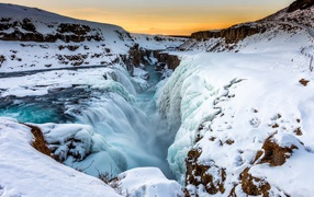 Заледеневший водопад у покрытых снегом берегов, Исландия