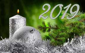 Красивый серебряный шар и свеча с еловой веткой на Новый год и Рождество 2019 