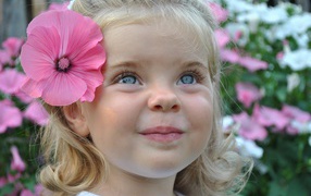 A cute little blonde girl with a flower in her hair