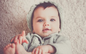 Маленький милый голубоглазый малыш в вязаном костюме