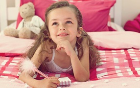 Замечтавшаяся маленькая девочка лежит на кровати