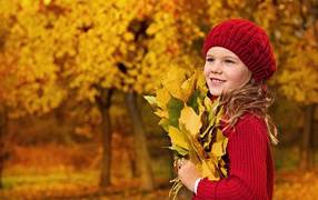 Девочка в красном берете с желтыми листьями в руках