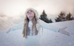 A girl in a white hat is happy with snow