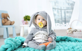 Маленький милый мальчик в костюме с пустышкой во рту