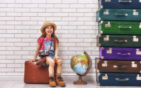 Маленькая девочка с фотоаппаратом сидит на чемодане