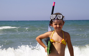 Маленькая девочка в очках и с ластами на море